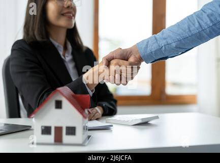 Les agents immobiliers et les clients se bousculer pour féliciter de la signature d'un contrat pour acheter une maison avec terre et assurance, poignée de main et bonne réponse Banque D'Images