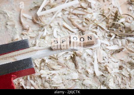 Cuillère de cuisson en bois autosculptée cuillère grattoir avec le mot - CUILLÈRE - sur un établi avec des copeaux de bois, Allemagne Banque D'Images