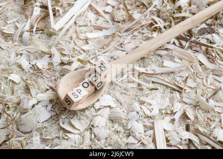 Cuillère de cuisson en bois autosculptée cuillère grattoir avec le mot - CUILLÈRE - sur un établi avec des copeaux de bois, Allemagne Banque D'Images