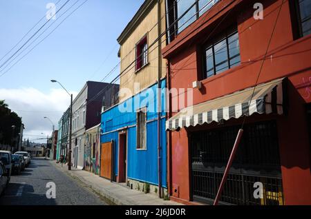 Valparaiso, Chili - février 2020 : maisons multicolores de deux étages dans l'un des quartiers de la ville sur la colline. Rue pavée dans la vieille ville avec des voitures garées Banque D'Images