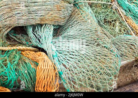 Un enchevêtrement de filets de pêche vert et orange rejetés dans le port de West Mersea, île Mersea, Essex, Royaume-Uni Banque D'Images