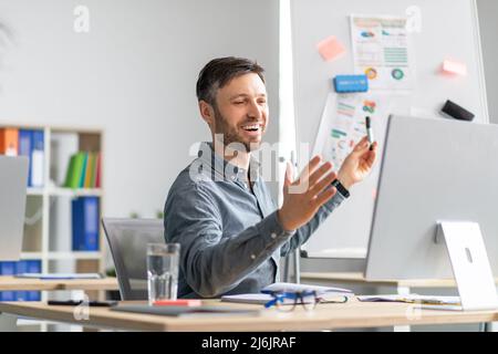Heureux homme mature faire la présentation, la démonstration de graphiques et de tableaux au bureau, parlant à l'ordinateur webcamera Banque D'Images