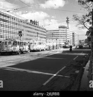 1960, historique, rue urbaine de Tokyo, Japon, montrant des autocars, des voitures et des tramways et des immeubles de bureaux modernes. Banque D'Images