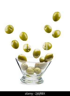 Grandes olives vertes sautant hors du bol en verre, sur fond blanc Banque D'Images