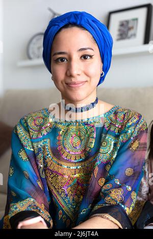 Portrait de la jeune femme musulmane à la maison. Elle porte une robe représentative de sa culture et un turban. Banque D'Images