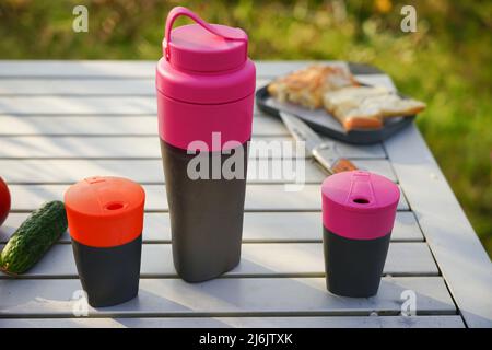 Un ensemble d'ustensiles de camping est placé sur une table pliante dans la nature. Conteneurs de liquides touristiques Banque D'Images