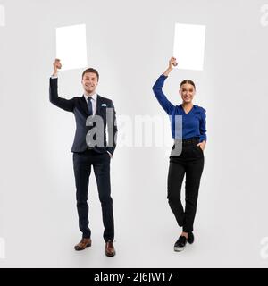 Hommes d'affaires tenant un panneau publicitaire blanc vierge au studio, montage d'images Banque D'Images