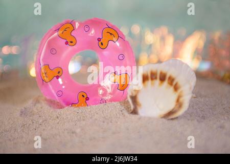 Cercle de natation décoratif avec coquillages près de lui, séjour dans le concept sable.Summertime. Banque D'Images