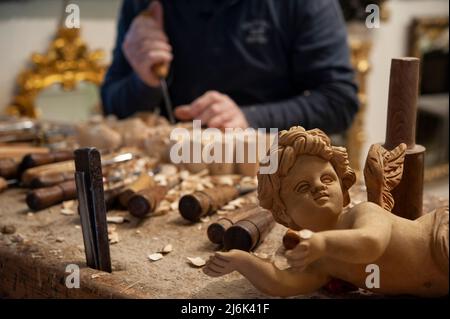 Maître menuisier au travail. Copeaux, gouges et burins de bois sur l'établi. Bois d'ange sculpté au premier plan. Banque D'Images