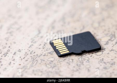 Gros plan de l'arrière d'une carte micro SD noire reposant sur une surface en pierre, des connecteurs du petit composant électronique de stockage i Banque D'Images