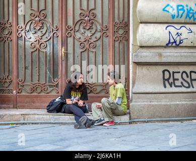 Bucarest, Roumanie - 04.08.2022: Deux jeunes adolescentes assises sur le trottoir dans le centre de Bucarest Banque D'Images
