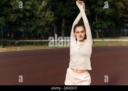 Le magnifique modèle féminin sportif est utilisé pour le sport en extérieur et regarde la caméra. Banque D'Images