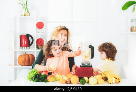 Mère et ses deux enfants mélangeant cocktail avec fruits et boisson smoothie, concept de fête des mères, Banque D'Images