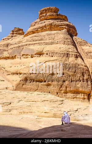 L'homme est assis sous les formations rocheuses de Madain Saleh, Hegra, Arabie Saoudite Banque D'Images