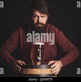 Un homme élégant qui boit de la bière sur fond noir. Brasseur. Émotif drôle de barbu hipster contient de la bière artisanale en bouteille. Banque D'Images