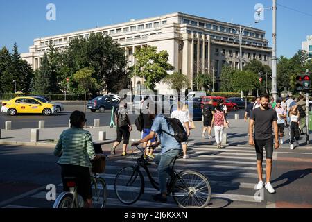 Bucarest, Roumanie - 17 août 2021 : les gens traversent la rue près du Palais Victoria qui abrite le siège du gouvernement roumain, à Bucarest Banque D'Images