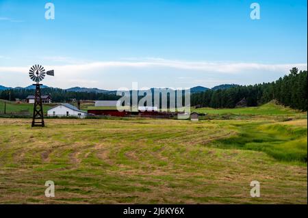 Ferme rurale dans le Dakota du Sud avec moulin à vent et hayfield. Banque D'Images