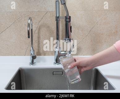fille ramassant un verre d'eau potable dans la cuisine Banque D'Images