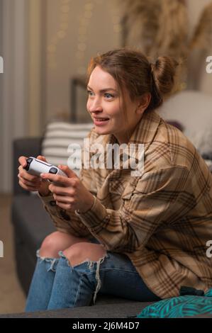 Une fille de joueur avec un joystick dans ses mains joue avec enthousiasme un jeu vidéo. Jeux en ligne avec des amis, concours, gagner, prix, surprises, jeunes Banque D'Images