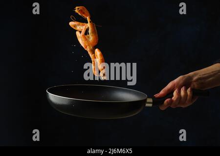 Des crevettes géantes dans une poêle en vol gelé sur fond noir. Alimentation gastronomique végétarienne saine, mode de vie sain. Fruits de mer. Recettes pour le restaurant an Banque D'Images