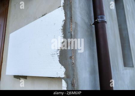 Installation de feuilles d'isolation en mousse de polystyrène sur le mur de la façade de la maison pour la protection thermique Banque D'Images