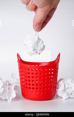 La main place les déchets dans le panier. Nettoyage du lieu de travail. Un homme nettoie le bureau. Banque D'Images