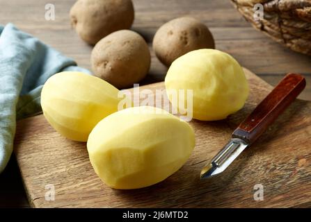 pommes de terre pelées crues sur une table de cuisine en bois rustique Banque D'Images