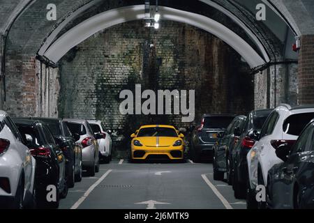 Un parking souterrain ou un parking dans une ville faisant bon usage de l'espace limité avec une voiture jaune vif proéminent Banque D'Images