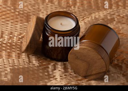 Bougies de soja dans un pot en verre brun avec un couvercle en bois. Aromathérapie. Bougie sur fond beige gros plan. Placer une étiquette. Cire et mèche. Décoration d'intérieur. Fait à la main. Désodorisant. Concept de bougie de soja Banque D'Images