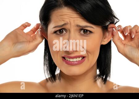 Belle jeune femme tirant ses oreilles avec ses doigts sur fond blanc Banque D'Images