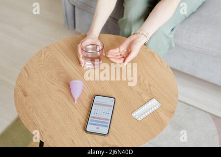 Jeune femme méconnaissable prenant des pilules contraceptives avec un verre d'eau Banque D'Images