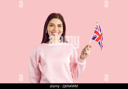 Bonne jeune femme anglaise isolée sur fond rose tenant le drapeau du Royaume-Uni et souriant Banque D'Images