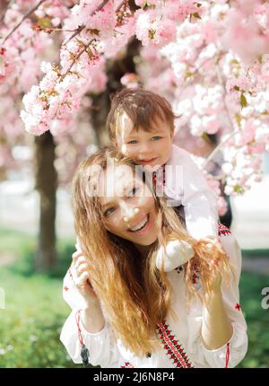 Bonne femme et enfant dans le jardin de printemps en fleurs. Concept de fête des mères Banque D'Images