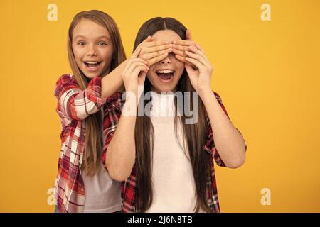 des enfants heureux dans une chemise à carreaux décontractée ayant les yeux de fermeture amusants sur fond jaune, devinez qui Banque D'Images