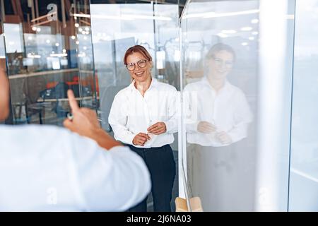 Une dame souriante qui a réussi écoute les commentaires de l'employé pendant la réunion d'affaires Banque D'Images