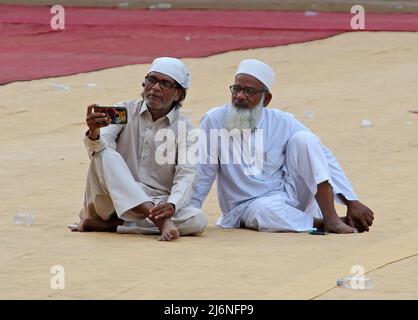 Des hommes musulmans vus à l'aide d'un téléphone mobile après avoir offert des prières d'Eid al-Fitr marquant la fin du Saint mois de jeûne du Ramadan au sol de la Société municipale de Brihanmumbai (BMC), à Mumbai. EID-al-Fitr est célébré par les musulmans du monde entier marquant la fin du mois de jeûne de l'aube au crépuscule pendant le mois Saint du Ramadan. Banque D'Images