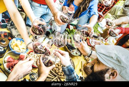 Vue de dessus des mains d'amis en toaster le verre de vin rouge et de s'amuser en plein air en dégustant un pique-nique de vin - les jeunes appréciant les vacances d'été ensemble Banque D'Images