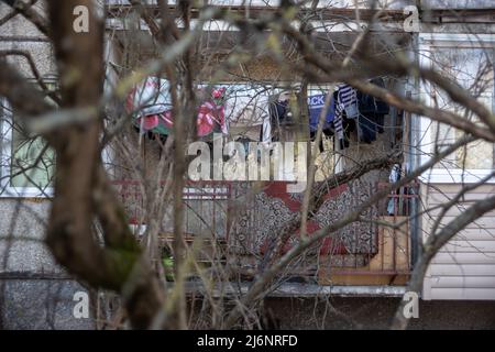 Séchage de linge sur le balcon, vue à travers les branches d'un arbre Banque D'Images