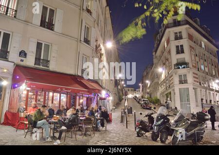 Paris, France - 12 novembre 2021 : les vieilles rues de Montmartre la nuit à Paris, France. Les Parisiens et les touristes apprécient la nourriture et les boissons dans la rue fre Banque D'Images