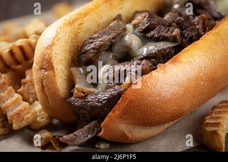 Gros plan du sandwich au cheesesteak de philadelphie, avec steak, fromage et oignons, sur un petit pain grillé et des frites Banque D'Images