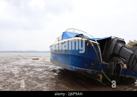 Face à la mer avec peu d'espoir d'être libéré bientôt - un bateau bleu coincé sur une plage boueuse Banque D'Images