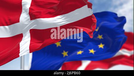 Détail du drapeau national du Danemark agitant dans le vent avec un drapeau flou de l'Union européenne en arrière-plan par temps clair. Démocratie et politique. E Banque D'Images