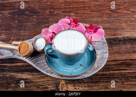 Gros plan sur une tasse blanche de boisson chaude laiteuse au salep sur fond de bois. Tasse de salep laiteuse traditionnelle boisson chaude de dinde à la cannelle servie dans un porcella Banque D'Images