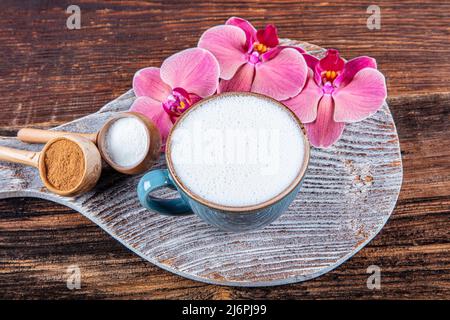 Gros plan sur une tasse blanche de boisson chaude laiteuse au salep sur fond de bois. Tasse de salep laiteuse traditionnelle boisson chaude de dinde à la cannelle servie dans un porcella Banque D'Images