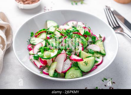 Salade de légumes frais avec radis, concombre et herbes fraîches sur fond gris clair. Banque D'Images