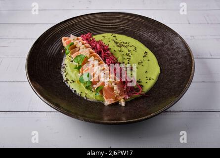 Gros plan sur un délicieux plat de tatatataki au saumon japonais recouvert de sésame et servi avec des bandes croustillantes. Isolé sur un fond moderne. Sélectif Banque D'Images