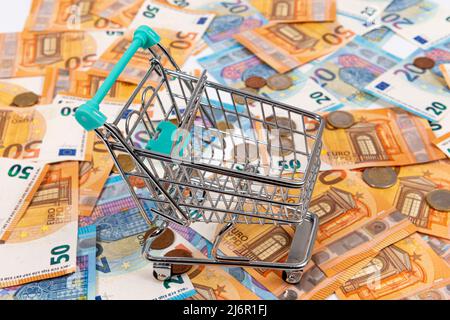 mini panier sur fond de pièces et billets en euros, gros plan Banque D'Images
