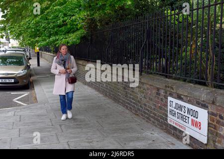 Femme marchant sur la rue St John's Wood High Street, Londres Banque D'Images