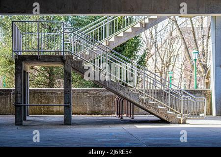 Escaliers en béton et en métal dans le parking couvert avec des branches d'hiver et des lampadaires verts à distance Banque D'Images