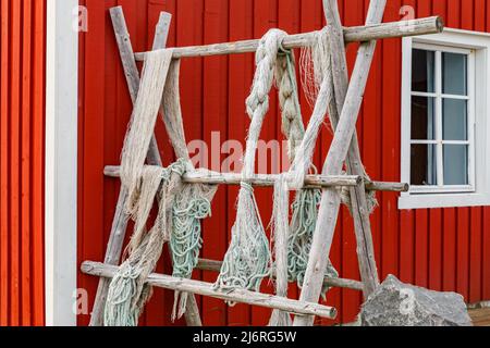 Îles Lofoten, filets de pêche accrochés à la clôture ou au porche, paysage norvégien classique, maison de couleur rouge, filets soigneusement choisis Banque D'Images